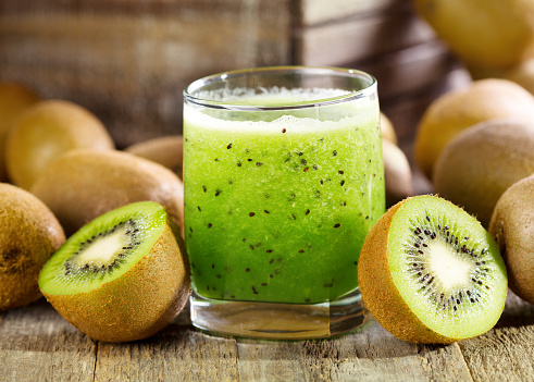 glass of kiwi juice with fresh fruits on wooden table