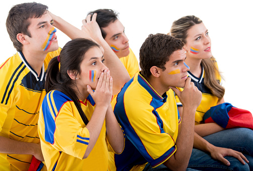 Worried group of Colombian football fans watching the game