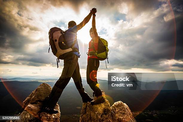 Couple On Top Of A Mountain Shaking Raised Hands Stock Photo - Download Image Now - Mountain Climbing, Mountain Peak, Mountain
