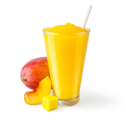 A peach and mango smoothie in a generic glass on a white background with a garnish of mangos and a peach slice on the side.