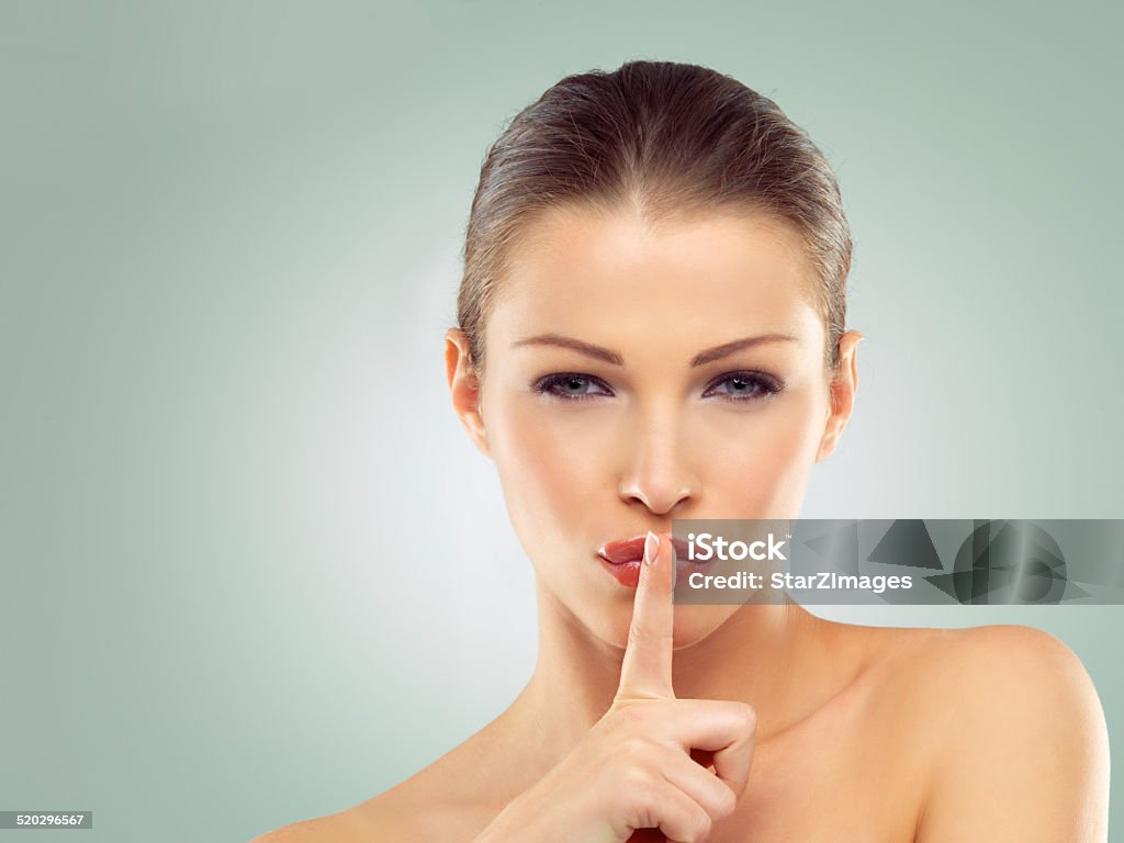 Shhh... don't tell Portrait of a beautiful young woman with her finger on her lips standing against a green backgroundhttp://azarubaika.com/iStockphoto/2014_05_09_Victoria_Beauty.jpg People Stock Photo