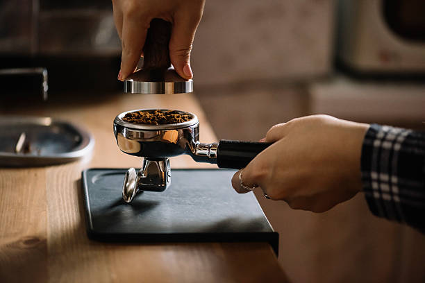 женский приготовленный кофе в portafilter подбивочная - tamping стоковые фото и изображения