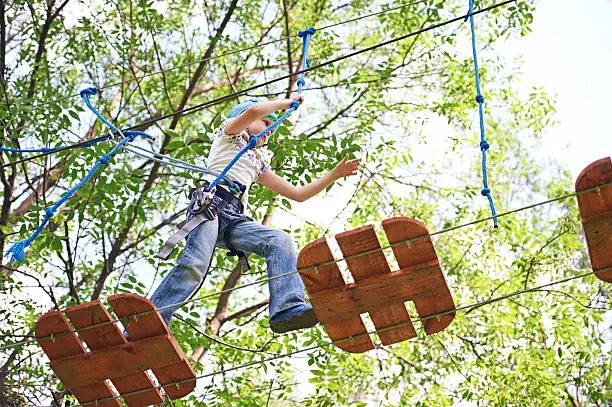 Girl is climbing to high rope structures in forest