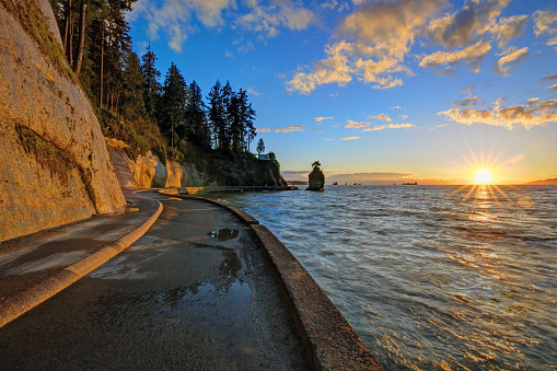 seawall and rock wall at sunset, with famous Siwash Rock in the sea water, Stanley Park, Vancouver, British Columbia, Canada