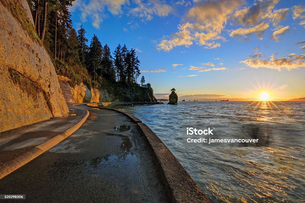 seawall and rock wall at sunset seawall and rock wall at sunset, with famous Siwash Rock in the sea water, Stanley Park, Vancouver, British Columbia, Canada Vancouver - Canada Stock Photo