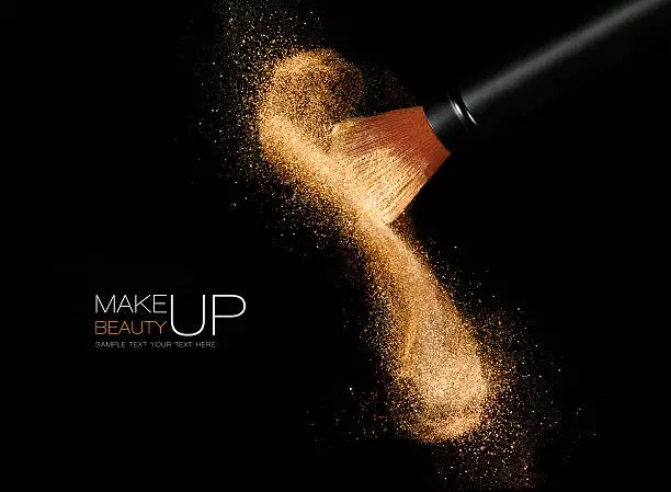 Photo of Cosmetics brush with glowing face powder. Dust explosion