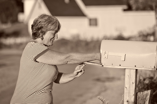 A woman checks her mailbox for mail during the day.