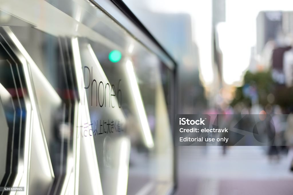 iPhone 6 Tokyo, Japan - October 17, 2014: People shopping in the upscale district of Ginza are reflected on the window of an Apple store advertising the release of iPhone 6. Apple Computers Stock Photo