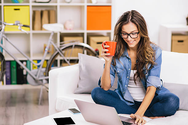 kobieta za pomocą laptopa w domu - biała kobieta czyta w okularach zdjęcia i obrazy z banku zdjęć