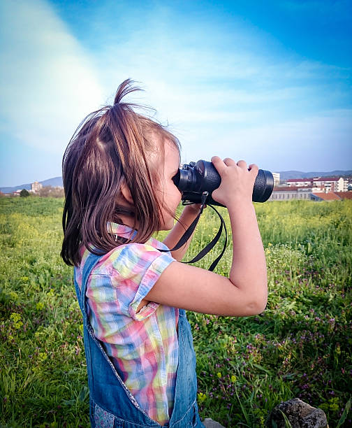 istock Little girl looking through binoculars outdoor 520323322