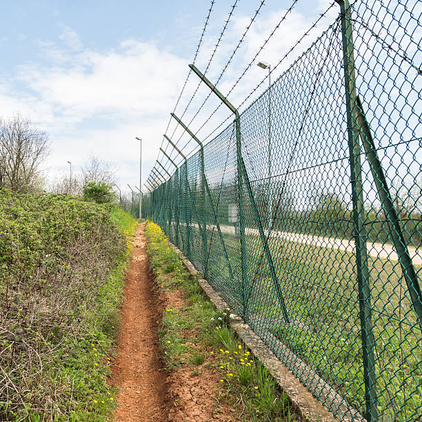istock Mesh fence topped with barbed wire. 520324880