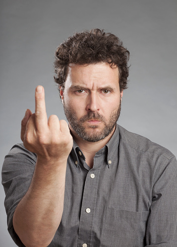 Man in grey shirt making rude hand gesture