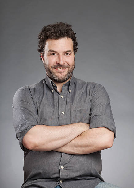 istock Man in grey shirt standing with arms crossed 520325125