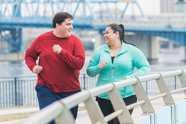 homem com excesso de peso e de uma mulher correndo na cidade - overweight - fotografias e filmes do acervo