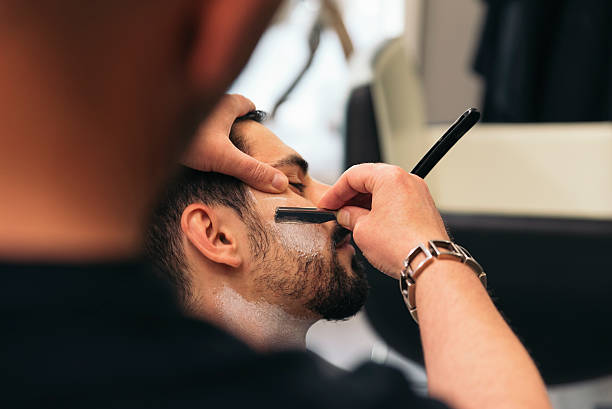 istock Bearded Man Getting Beard Haircut With A Razor By Barber 520325998