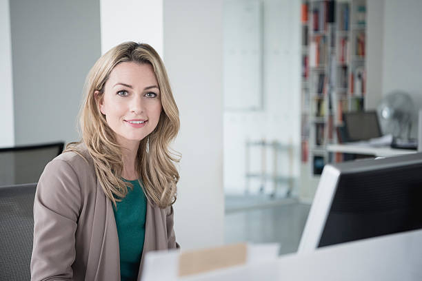 istock Businesswoman sitting at desk with computer smiling towards camera 520327320