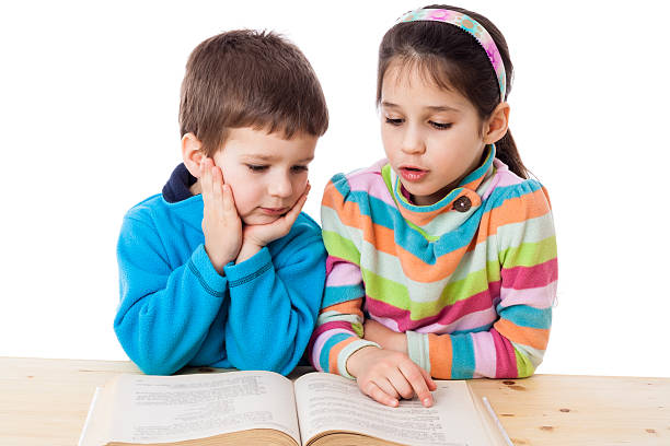 istock Two kids reading the book at the table 520328370