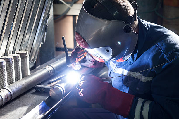 Closeup of man wearing mask welding in a workshop Closeup of man wearing mask welding in a workshop stainless steel factory stock pictures, royalty-free photos & images