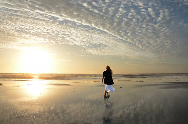 istock Woman walking on the beach at sunrise. 520329516