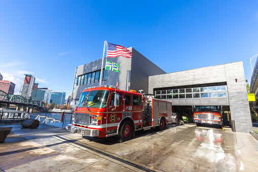 Fire Station in Boston, Massachusetts, USA.  There are pedestrians on the sidewalk and a fire engine driving out of the garage.