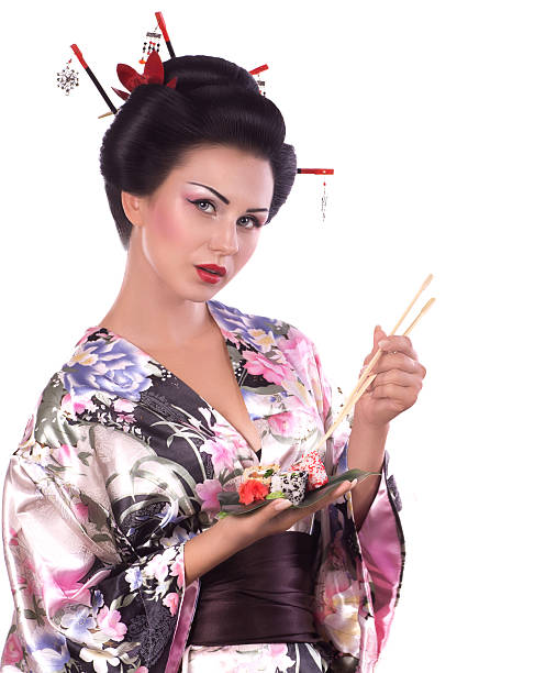 Young woman in Japanese kimono with chopsticks and sushi roll stock photo