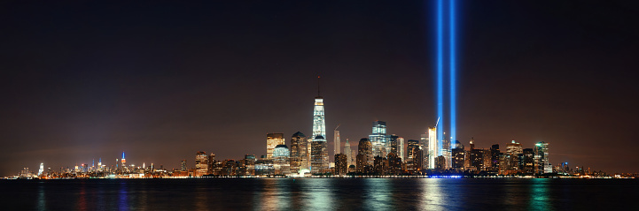 New York City downtown skyline at night panorama over Hudson River and September 11 tribute light