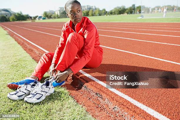 Track And Field Athlete Putting On Shoes Stock Photo - Download Image Now - Women, One Woman Only, Sport