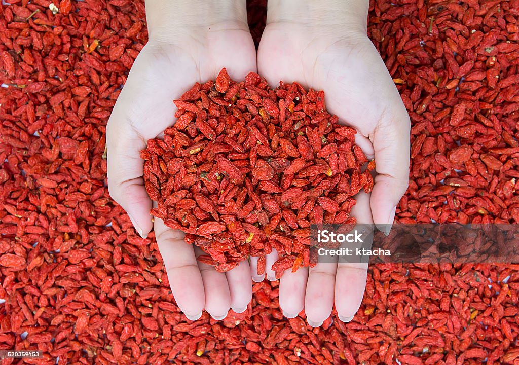 woman holding goji berries on goji berries background Goji Berry Stock Photo