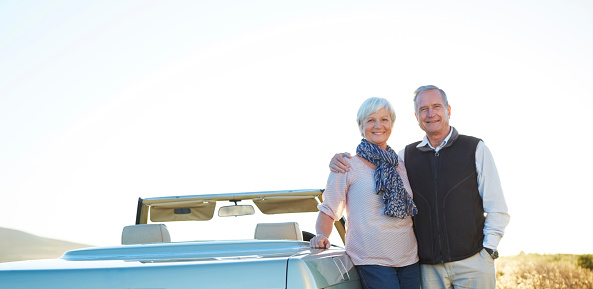 Portrait of an affectionate senior couple standing by their car by the side of the road