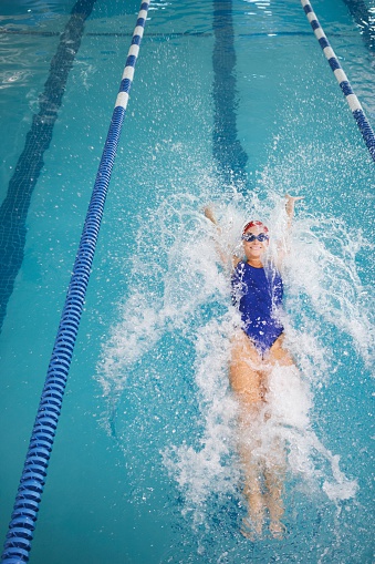 Person, freestyle and swimming in pool for sports competition, challenge and fitness training. Athlete, woman and swimmer in workout exercise for water race stroke, speed and triathlon championship