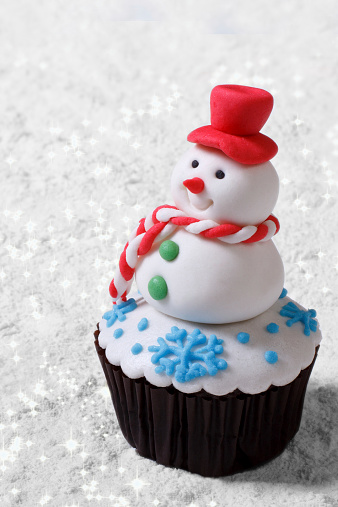 Cupcake Christmas snowman on white snow. vertical