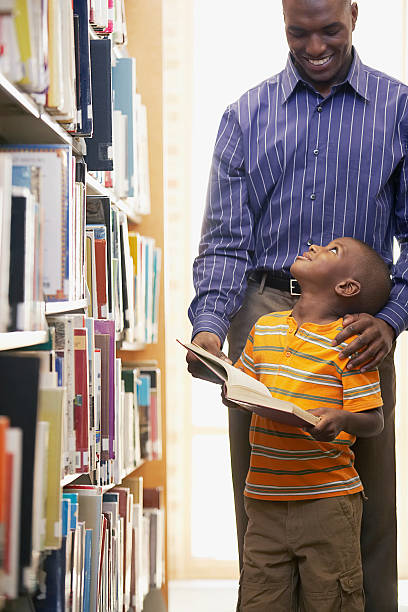 отец и сын в библиотеке - men african descent looking up smart casual стоковые фото и изображения