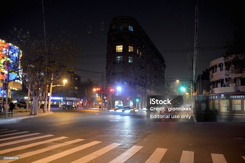 Road junction at Wukang Mansion, old French concession of Shanghai Shanghai, China - December 7, 2014: Road junction in Xujiahui district at night. In the background, the historic Wukang Mansion, a landmark in the French Concession area of Shanghai. Formerly known as the Normandie Apartments, is a protected historic apartment building. Apartment Stock Photo