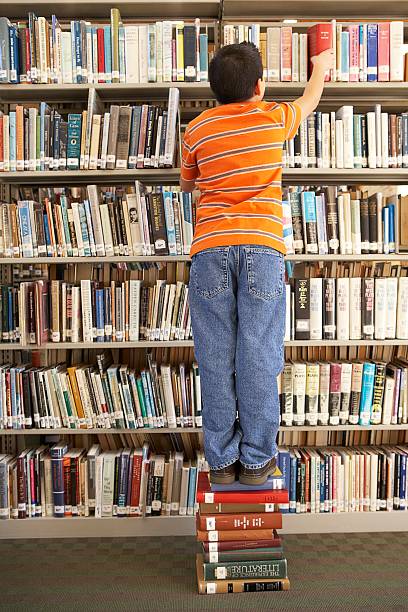 istock Trying to reach a book on the top shelf 520367342