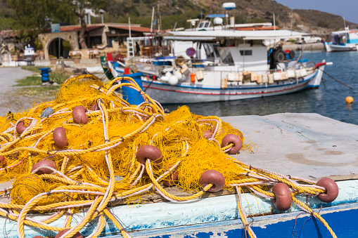 Fishing nets and Greek fishing boats mooring in port in sunrise light, Crete island, Greece