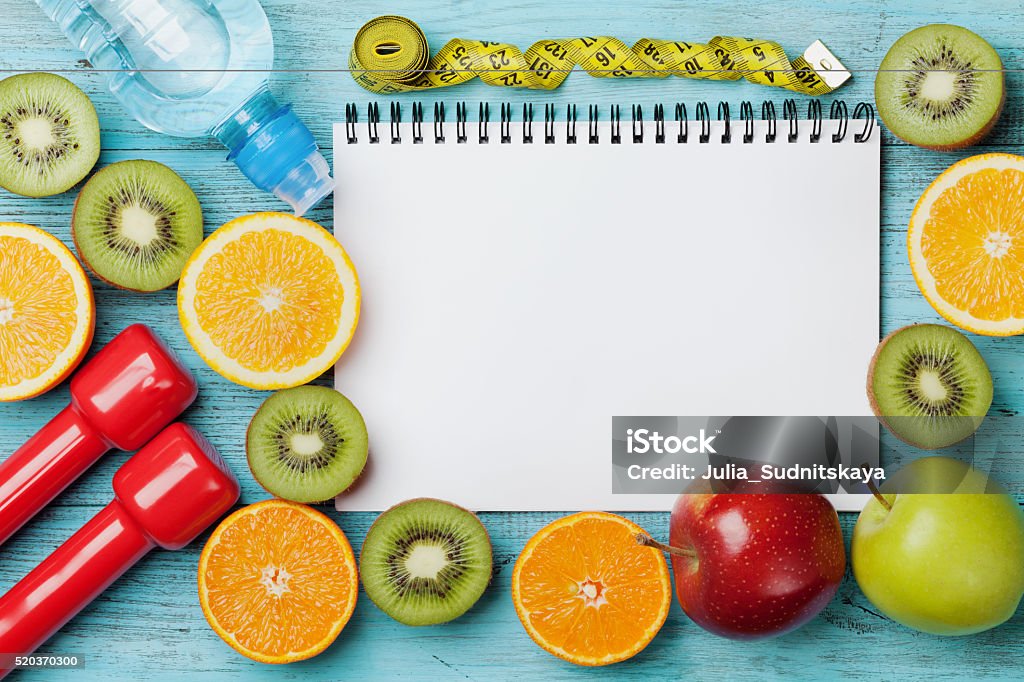 Diet plan, menu or program, weight loss and detox concept Diet plan, menu or program, tape measure, water, dumbbells and diet food of fresh fruits on blue background, weight loss and detox concept, top view Nutritionist Stock Photo