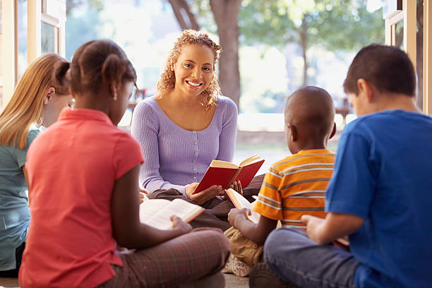 bibliothekar liest einer gruppe von kindern vor - bible holding reading book stock-fotos und bilder