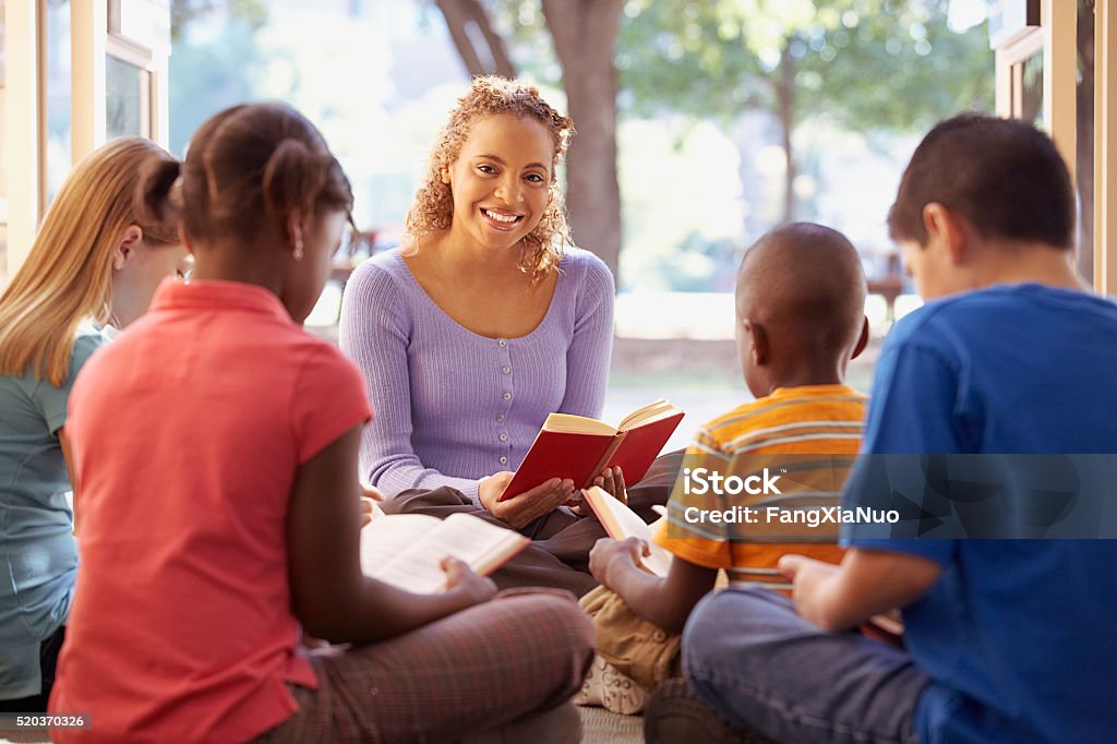 Librarian reads aloud to a group of children Bible Stock Photo