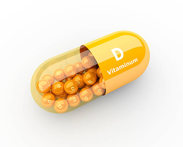 vitamina d cápsula tendido sobre un escritorio - vitamin d fotografías e imágenes de stock