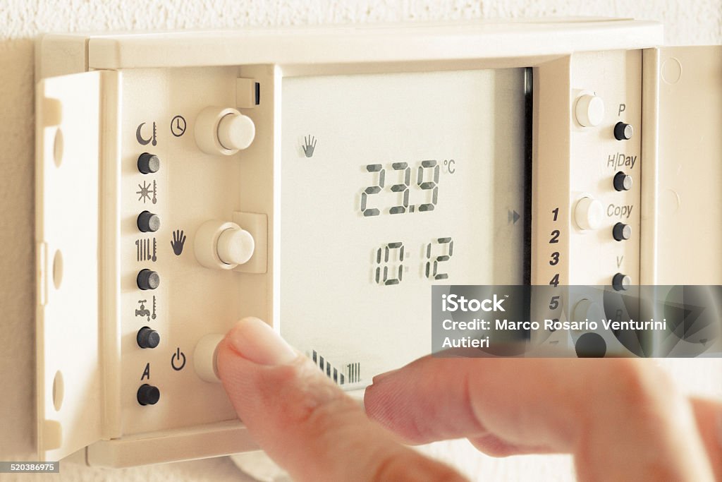 Setting up the thermostat for the winter The cold season has come and I need to set the house thermostat for heating the rooms. Tilted plane of focus (all the panel is on focus, not all the hand is) Arranging Stock Photo