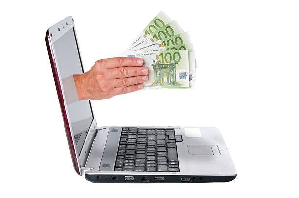 mano con los billetes de euro proviene de la pantalla del ordenador portátil - euro symbol currency internet computer keyboard fotografías e imágenes de stock