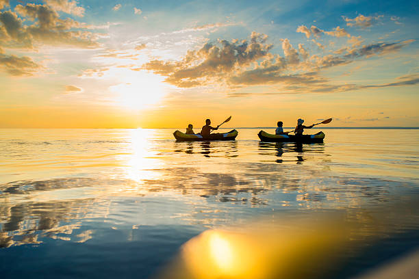 Silhouette of family enjoy sea kayaking in the sunset.