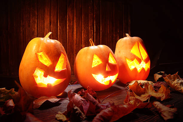 istock Jack o lanterns  Halloween pumpkin face on wooden background 520393841