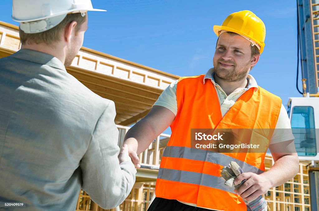 Architect and construction worker shaking hands. Construction Industry Stock Photo