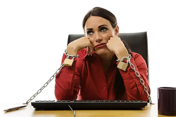 businesswoman chained to her office desk at work