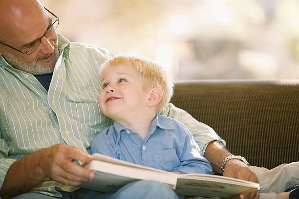 grand-père lisant avec son petit-fils - grandparent family reading inside of photos et images de collection