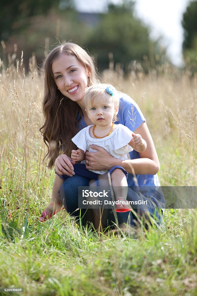 Mother and Toddler Child in Grassy Meadow Beautiful mother with long hair exploring nature with her baby girl. 12-17 Months Stock Photo