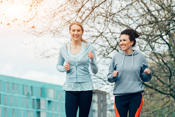 istock Two young female running together in city environment 520411374