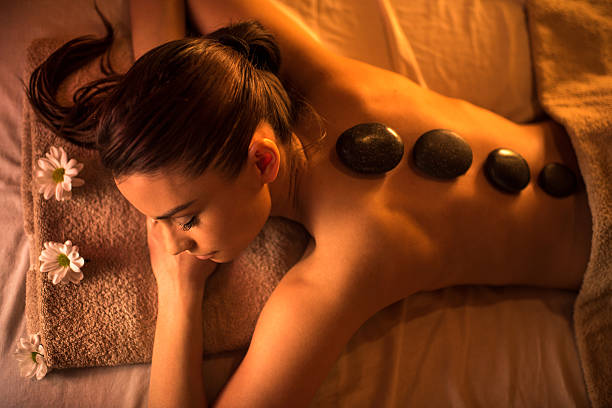 Above view of young woman during lastone therapy at spa. High angle view of young woman relaxing at the spa with eyes closed and receiving hot stone therapy. hot stone massage stock pictures, royalty-free photos & images