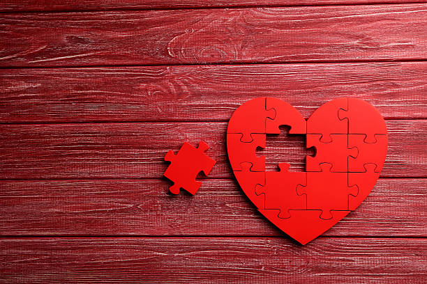 istock Red puzzle heart on red wooden background 520411904